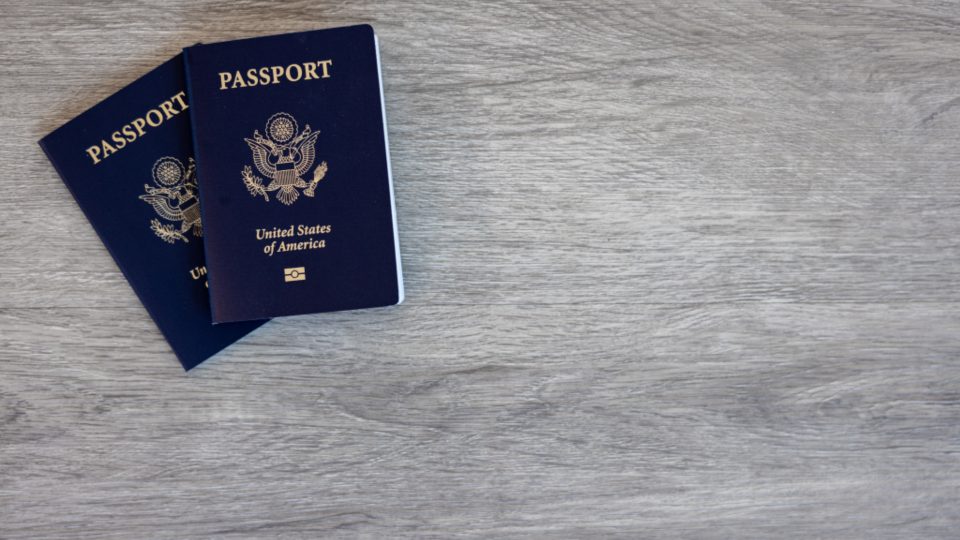 Two passports lying on a light wooden table
