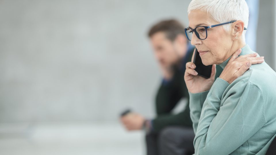 A worried woman with glasses making a phone call
